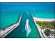 Aerial view of a boat entering a turquoise inlet, with sandy beaches and parking areas visible at 5003 Southern Pine Cir, Venice, FL 34293