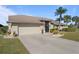 Two-car garage, light beige exterior, and lush green landscaping at 5003 Southern Pine Cir, Venice, FL 34293