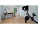 Home gym with Peloton bike, desk, and wood flooring at 5003 Southern Pine Cir, Venice, FL 34293