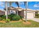 Tan house with palm trees, landscaped yard, and two-car garage at 121 Amora Ave, Venice, FL 34285