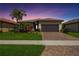 One-story home with gray garage door, landscaping, and brick driveway at 13510 Esposito St, Venice, FL 34293