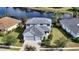 Two-story house with gray roof and light blue exterior, situated on a tree-lined street next to a lake at 21042 Anclote Ct, Venice, FL 34293