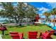 Outdoor seating area with red chairs and green lawn at 21042 Anclote Ct, Venice, FL 34293