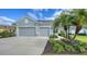 Two-car garage with gray exterior and landscaping, featuring a palm tree and manicured lawn at 21042 Anclote Ct, Venice, FL 34293