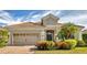 Tan house with brown roof, 2-car garage, and lush landscaping at 21208 Sandal Foot Dr, Venice, FL 34293