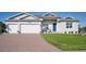 Two-car garage, light gray house, blue door, and landscaped lawn at 9401 President Cir, Port Charlotte, FL 33981