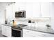 Modern white kitchen with granite countertops and stainless steel appliances at 9401 President Cir, Port Charlotte, FL 33981