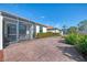 Large backyard patio with brick pavers, landscaping, and screened enclosure at 9847 Haze Dr, Venice, FL 34292