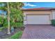 White garage door with red brick paver driveway and lush landscaping at 9855 Haze Dr, Venice, FL 34292