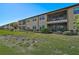 Tan building exterior with screened balconies, lush landscaping, and a grassy lawn at 10055 Crooked Creek Dr # 102, Venice, FL 34293