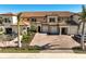 Three-unit building with attached garages, paver driveway, and tropical landscaping at 10055 Crooked Creek Dr # 102, Venice, FL 34293