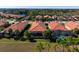 Aerial view of a residential area featuring houses with red tile roofs and swimming pools at 115 Avalini Way, North Venice, FL 34275