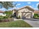 Tan single-story home with a two-car garage and landscaped lawn at 115 Avalini Way, North Venice, FL 34275