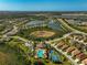 Aerial view of community with pool, tennis courts, and lake at 232 Benedetto Ct, Nokomis, FL 34275