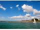 Scenic coastal view with sailboat and beach under a bright, cloud-filled sky at 305 Rio Terra, Venice, FL 34285