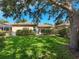 Manicured backyard with healthy lawn, verdant perimeter hedges, mature shade tree, and screened in porch at 305 Rio Terra, Venice, FL 34285