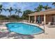 Community pool with lounge chairs, adjacent building, a fence, palm trees, and clear blue water at 305 Rio Terra, Venice, FL 34285
