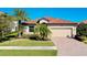 Single-story home with tile roof, palm trees, and brick driveway at 12704 Richezza Dr, Venice, FL 34293