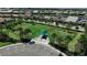 Aerial of a fenced dog park with seating and shade, surrounded by lush greenery and community homes at 12837 Oriago St, Venice, FL 34293