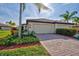 Two-car garage with a brick driveway and tropical landscaping at 20272 Tesoro Dr, Venice, FL 34293