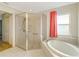 Bright bathroom featuring tiled shower, soaking tub, and window with natural light at 6502 Whelan St, Englewood, FL 34224