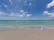 Expansive beach view showcasing the pristine shoreline and the clear turquoise waters under a bright, cloudy sky at 705 Armada N Rd, Venice, FL 34285