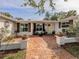 Inviting brick courtyard with a yellow front door, shutters, and outdoor seating area at 705 Armada N Rd, Venice, FL 34285