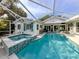 Outdoor pool and spa area surrounded by a screened enclosure and lush landscaping at 705 Armada N Rd, Venice, FL 34285