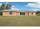 One-story house with light peach walls, covered patio, and grassy yard at 13421 Gershwin Ln, Port Charlotte, FL 33981
