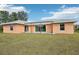 Exterior view of a peach house with a backyard and pergola at 13421 Gershwin Ln, Port Charlotte, FL 33981