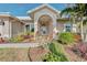 Front entrance with arched entryway, lush landscaping, and walkway at 1558 Belfry Dr, Venice, FL 34292