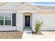 Front door entrance with dark blue door, shutters, and landscaping at 16766 Carlton Pond St, Wimauma, FL 33598