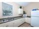Small galley kitchen with white cabinets, double sink, microwave, and refrigerator at 201 Auburn Woods Cir, Venice, FL 34292