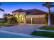 Three car garage home with paver driveway at dusk at 20450 Passagio Dr, Venice, FL 34293
