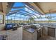 Outdoor kitchen with built-in grill, bar seating, and a fire pit at 20450 Passagio Dr, Venice, FL 34293