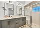 Modern bathroom with dual vanities, gray cabinets, and a walk-in shower at 2899 Ensenada Ln, North Port, FL 34286