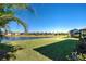 Scenic backyard view overlooking a lake with lush landscaping and houses at 295 Cassano Drive, Nokomis, FL 34275