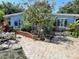 Charming home with vibrant blue paint, white windows, bridge walkway, and lush tropical landscaping at 3421 Normandy Dr, Port Charlotte, FL 33952