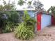 Light blue house with red door, surrounded by tropical plants and a brick paved area at 3421 Normandy Dr, Port Charlotte, FL 33952