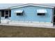 Charming blue single-story home featuring awnings, a well-maintained yard, and an attached carport at 356 Longwood Dr, Venice, FL 34285
