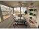 Sunroom with sliding glass windows is furnished with a table and chairs and shelving with plants at 356 Longwood Dr, Venice, FL 34285