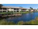 Building and canal view with lush landscaping and dock at 380 Three Lakes Ln # F, Venice, FL 34285