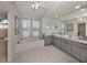 Large bathroom with gray vanity, a soaking tub, and a double sink at 498 Lake Of The Woods Dr, Venice, FL 34293