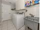 Laundry room with side-by-side washer and dryer, utility sink, and overhead shelving at 498 Lake Of The Woods Dr, Venice, FL 34293