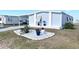 Gray manufactured home with landscaped flowerbeds and a paved driveway at 113 Lakeview Dr, North Port, FL 34287