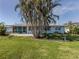 House with a large grassy lawn and tropical landscaping at 1226 Pine Needle Rd, Venice, FL 34285