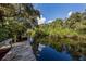 Wooden dock leads to a calm river surrounded by lush foliage at 1226 Pine Needle Rd, Venice, FL 34285