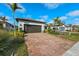 Single story house with 2-car garage, paver driveway, and tropical landscaping at 13756 Vadini St, Venice, FL 34293