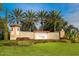 Stone sign at Venetian Falls community entrance with lush landscaping and palm trees at 1841 Batello Dr, Venice, FL 34292