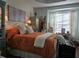 Spacious bedroom with burnt orange comforter, large windows, and decorative cabinets at 1890 San Trovaso Way, Venice, FL 34285